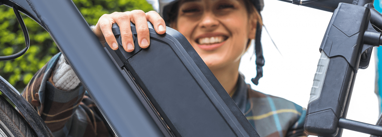 Vrouw met helm pakt accu van elektrische fiets